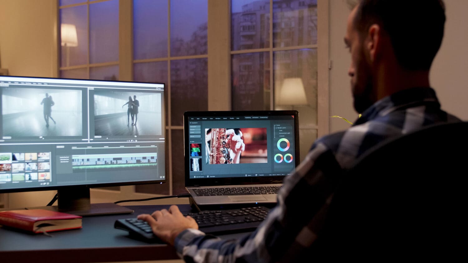 A man uses two computer screens to create an eCommerce video marketing campaign with graphs and video production software.