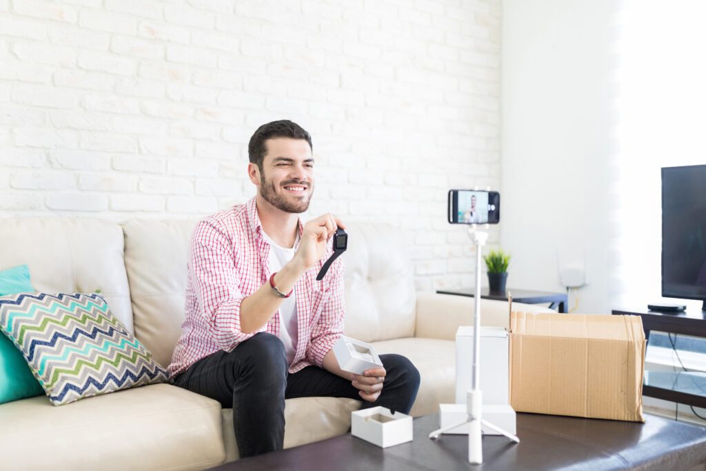 A man creates a product demo video for a smartwatch using his camera phone on a tripod on top of his coffee table. 