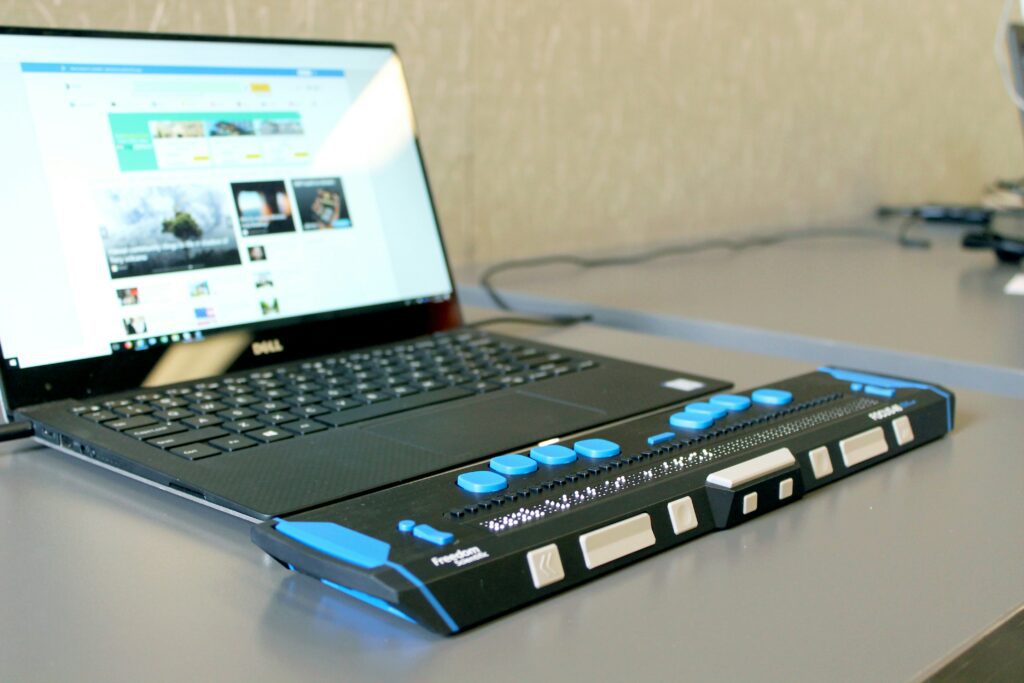 Laptop with a refreshable braille display used for accessible digital content under the European Accessibility Act in France.